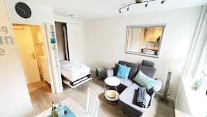 A compact living space with a sofa, a small dining table, a bed, and a kitchenette in the background. - Modern vacation apartment with sauna, solarium and heated indoor pool in Westerland (Westerland)