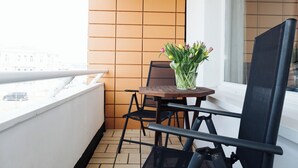 Uma varanda com uma mesa, cadeiras e um vaso de flores.