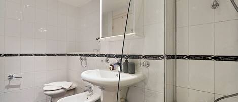 Ein modernes Badezimmer mit Toilette, Bidet, Waschbecken und Dusche.