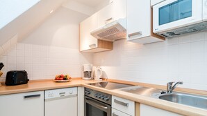 Et moderne køkken med hvide skabe, en stålvask, indbygget mikroovn og en brødrister.
