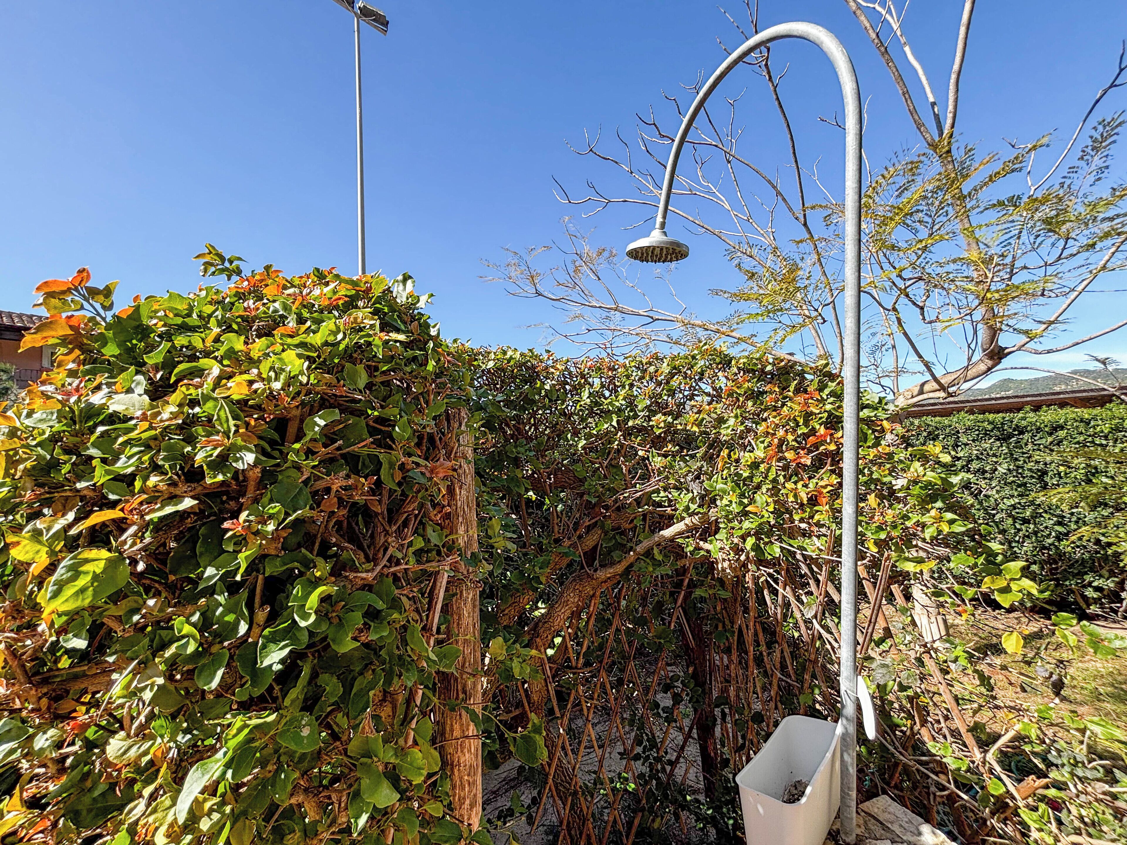 Un área de jardín con un farol de metal y un cubo de basura blanco.