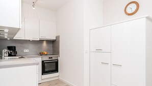 Eine moderne Küche mit weißen Schränken, einem Backofen und einer Kaffeemaschine.