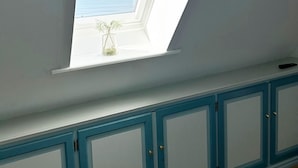 A skylight window with a small vase of flowers on a white wall. - Exclusive vacation apartment with a view of the sea (Wenningstedt)