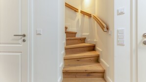 A staircase with wooden steps and a wooden handrail, leading to an upper floor. - This beautiful and new terraced house is centrally located in Westerland (Westerland)