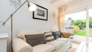 A modern living room with a beige sofa, a floor lamp, and a framed picture on the wall. - Comfortable vacation apartment with terrace and garden in Wenningstedt (Wenningstedt)