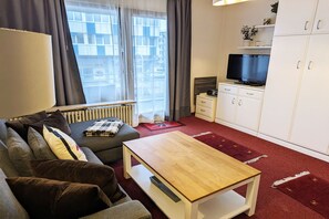 A modern living room with a sofa, a coffee table, a TV, and a cabinet. - Cozy vacation apartment with sauna and heated indoor pool in Westerland (Westerland)