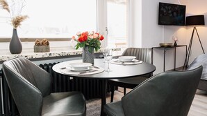 Un comedor moderno con una mesa redonda, sillas tapizadas en gris y un jarrón con flores.
