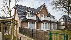 Een woonhuis met een bakstenen gevel, een pannendak en een omheinde tuin.