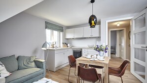 Een modern appartement met een eethoek, kitchenette en een woonkamer met een bank en een lamp.