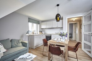 Eine moderne Wohnung mit Essbereich, Küchenzeile und Wohnzimmer mit Sofa und Lampe.