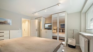 Een moderne slaapkamer met een groot bed, een televisie en een inloopkast.