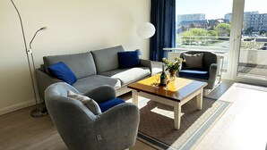 En moderne stue med en grå sofa, et træsofabord og en grå lænestol.
