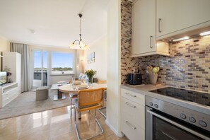 A modern kitchen with a tiled backsplash, stainless steel appliances, and a dining area with a table and chairs. - Comfortable apartment with modern furnishings in Haus Ankerlicht, Westerland (Westerland)