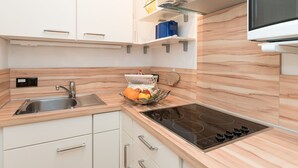 A modern kitchen with white cabinets, a stainless steel sink, a built-in stove, and a fruit basket on the counter. - Comfortable apartment with balcony, elevator and parking space in Westerland (Westerland)