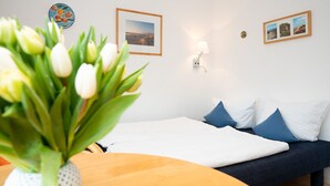A bedroom with a bed, a bedside table with a vase of flowers, and a wall-mounted lamp. - Comfortable apartment with balcony, elevator and parking space in Westerland (Westerland)