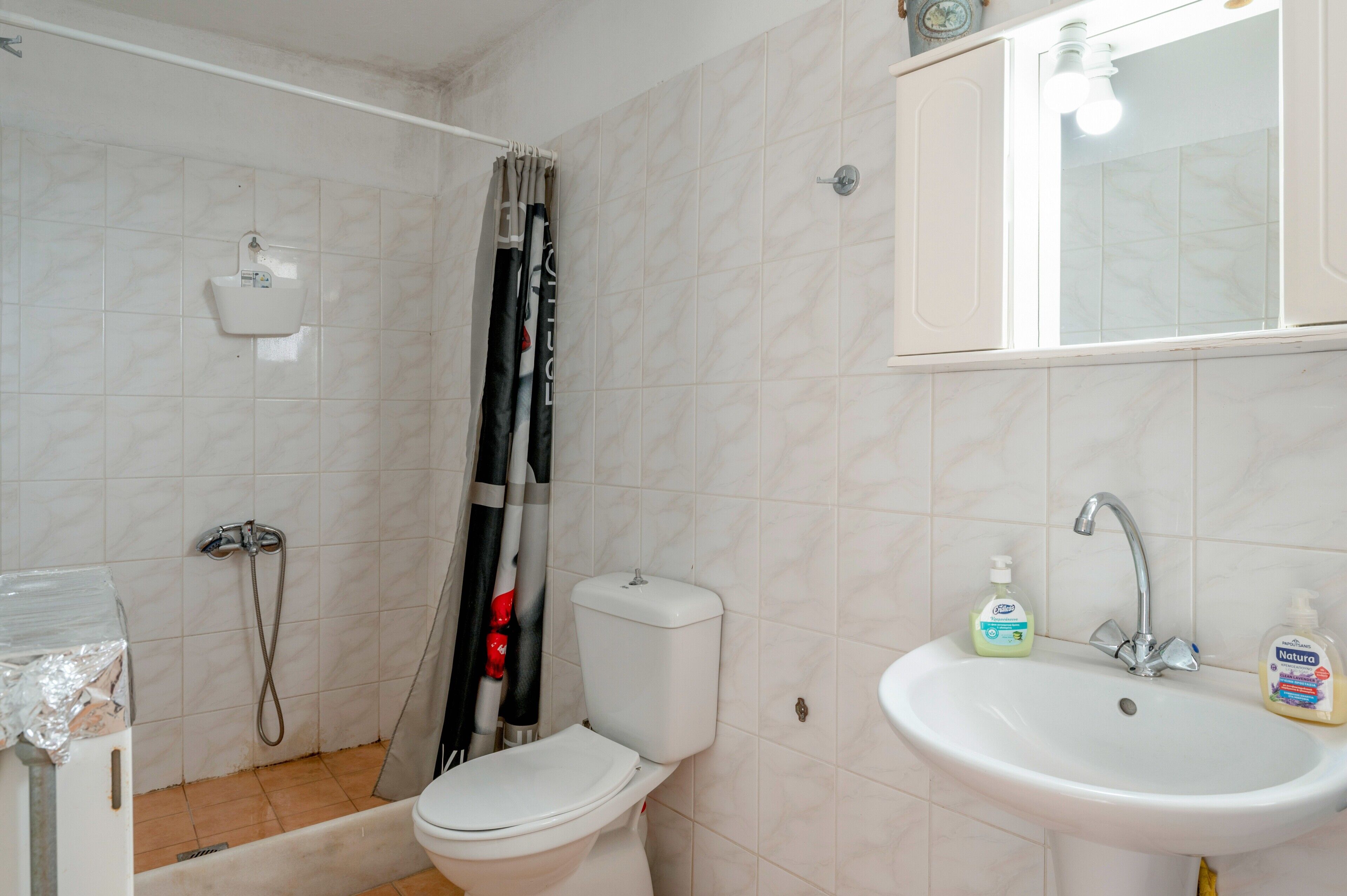A bathroom with a shower, toilet, sink, and a mirror.