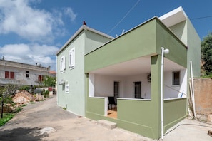A two-story building with a green exterior, a balcony, and a visible window. - Apartment 'Traditional House in Velies, Monemvasia' with Mountain View, Wi-Fi & AC (Áyios Sarándos)