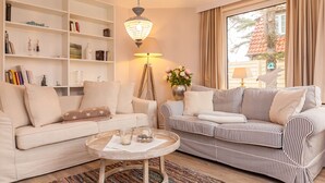 Ein Wohnzimmer mit zwei Sofas, einem Couchtisch, einem Bücherregal und einer Chandelieber.