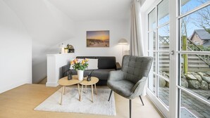 Un salon moderne avec un canapé, un fauteuil, une table basse et un tableau accroché au mur.