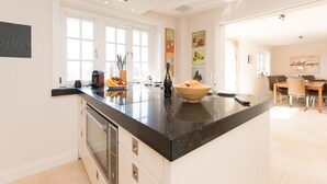 Eine moderne Küche mit einer großen Kochinsel, weißen Schränken und einem Essbereich mit Tisch und Stühlen.