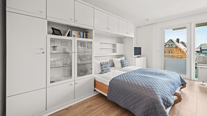 Un dormitorio moderno con una cama grande, armario empotrado y televisor.