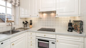 Et moderne køkken med hvide skabe, en stålvask og en indbygget ovn.