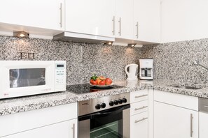 A compact kitchen with a microwave, stove, and coffee maker. - Cozy vacation apartment on the 1st floor in a quiet location in Wenningstedt (Wenningstedt)