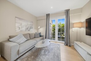A modern living room with a grey sofa, a coffee table, and a TV on a stand. - Comfortable penthouse in Westerland with terrace and modern furnishings (Westerland)