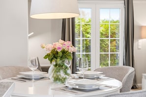 A dining table set with plates, cutlery, and a vase of flowers.
