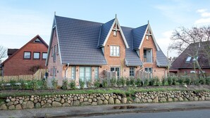 Une maison à deux étages, dotée d’un toit à forte pente, d’une façade en briques et d’un mur en pierre à l’avant.