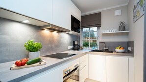 Une cuisine moderne avec des armoires blanches, une cuisinière encastrée et une grande fenêtre offrant une vue sur l’extérieur.