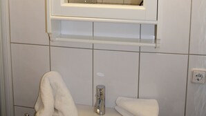 Ein Badezimmer mit einem weißen Waschbecken, zwei Wandleuchten und einem Spiegel über dem Waschbecken.