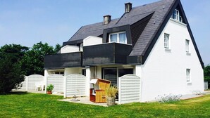 Een modern huis met twee verdiepingen, een donker dak, witte buitenmuren en een omheinde achtertuin.