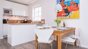 Een moderne keuken met witte kastjes, een houten eiland en een eethoek met witte stoelen en een houten tafel.