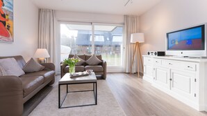 Een moderne woonkamer met een bank, een salontafel, een televisie en een kast.
