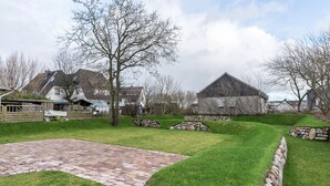 Un jardin bien entretenu, doté d’une terrasse dallée, de bordures en pierre et d’une pelouse.