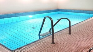 En swimmingpool med blå kakelplattor och ett kaklat poolområde.