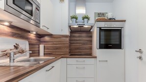Eine moderne Küche mit eingebautem Backofen, Edelstahlgeräten, Holz Arbeitsplatten und weißen Schränken.