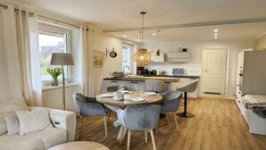Uma sala de estar moderna e bem iluminada, com área de refeições, cozinha e um espaço de estar aconchegante.