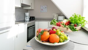 A kitchen with white cabinets, a coffee maker, and a fruit bowl on the counter. - 3-room apartment on the upper floor in a quiet location in Alt-Westerland (Westerland)