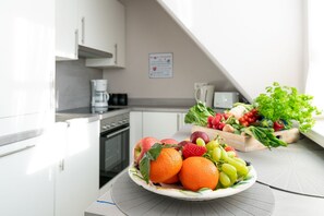 A kitchen with white cabinets, a coffee maker, and a fruit bowl on the counter. - 3-room apartment on the upper floor in a quiet location in Alt-Westerland (Westerland)