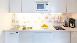 A modern kitchen with white cabinetry, a built-in microwave, a sink, and a coffee maker. - Bright and cozy vacation apartment directly on the beach crossing in Westerland (Westerland)