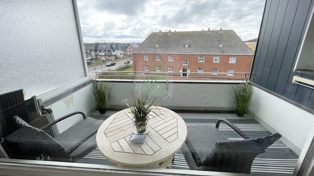 A balcony with a round table, two chairs, and a potted plant. - Bright and cozy vacation apartment directly on the beach crossing in Westerland (Westerland)