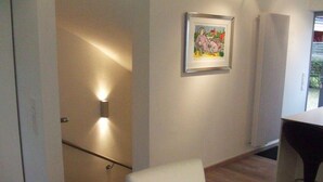 A modern room with a white chair, a framed picture on the wall, and a radiator. - Spacious 3-room apartment with terrace and garden in Wenningstedt (Wenningstedt)