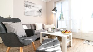 Ein modernes Wohnzimmer mit einem grauen Sofa, einem grauen Sessel und einem weißen Couchtisch mit Obst.