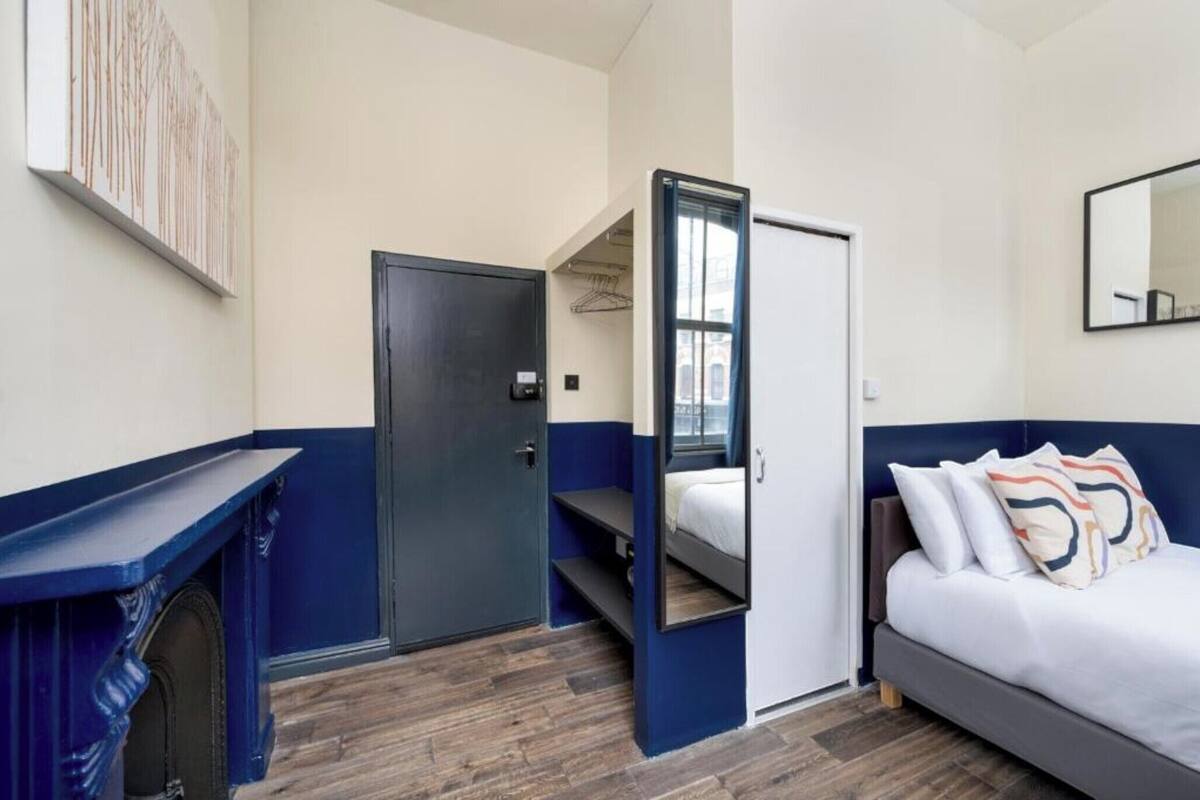 A bedroom with a bed, a wardrobe, a mirror, and a door.
