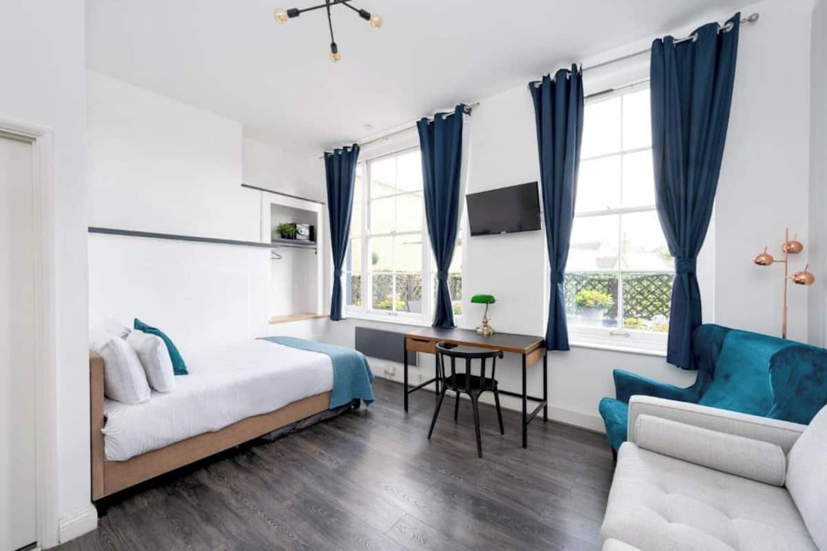 A modern room with a bed, a desk, a chair, and a sofa.
