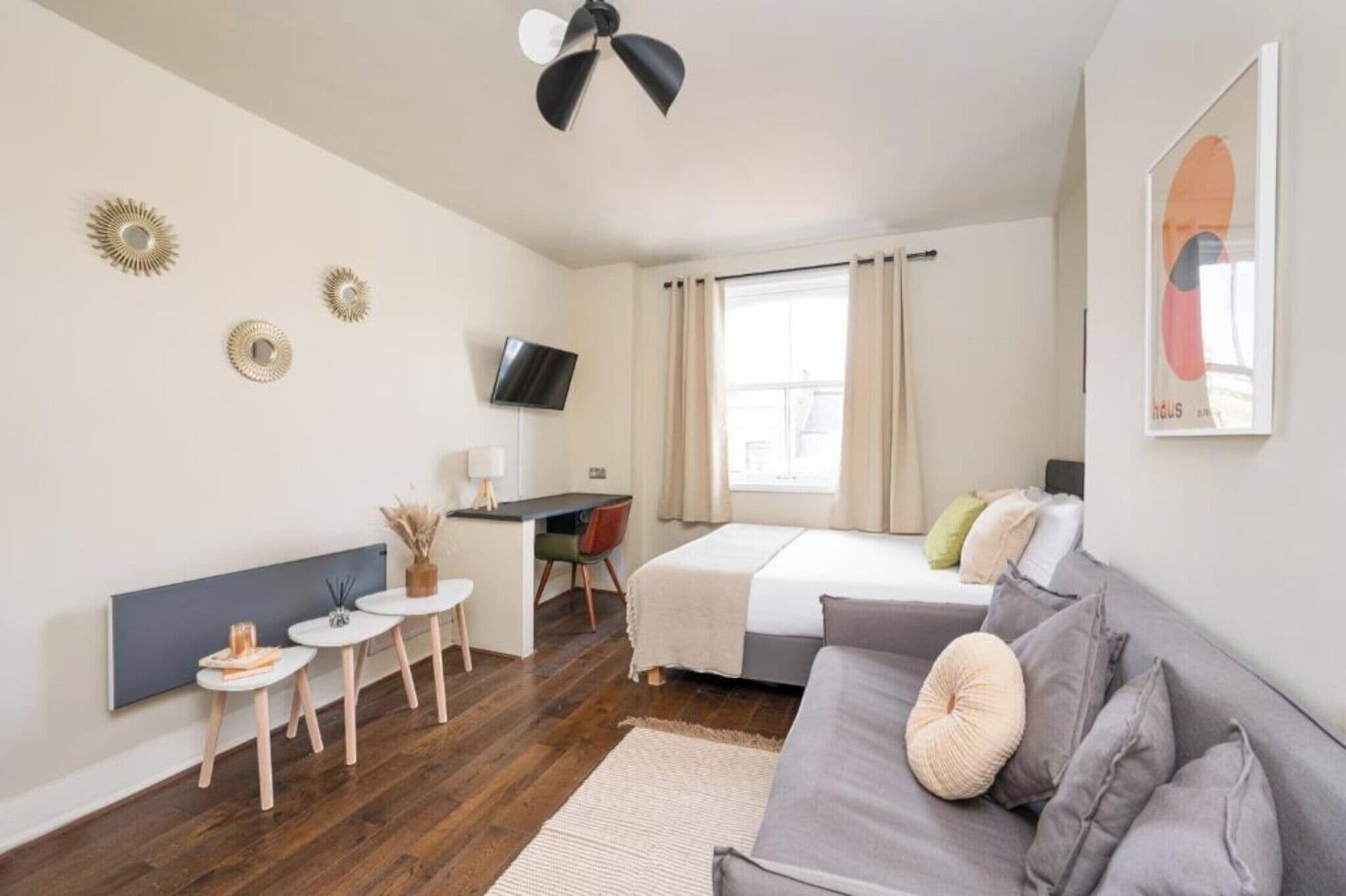 Een moderne, goed verlichte kamer met een bed, een bureau, een televisie en een bank.