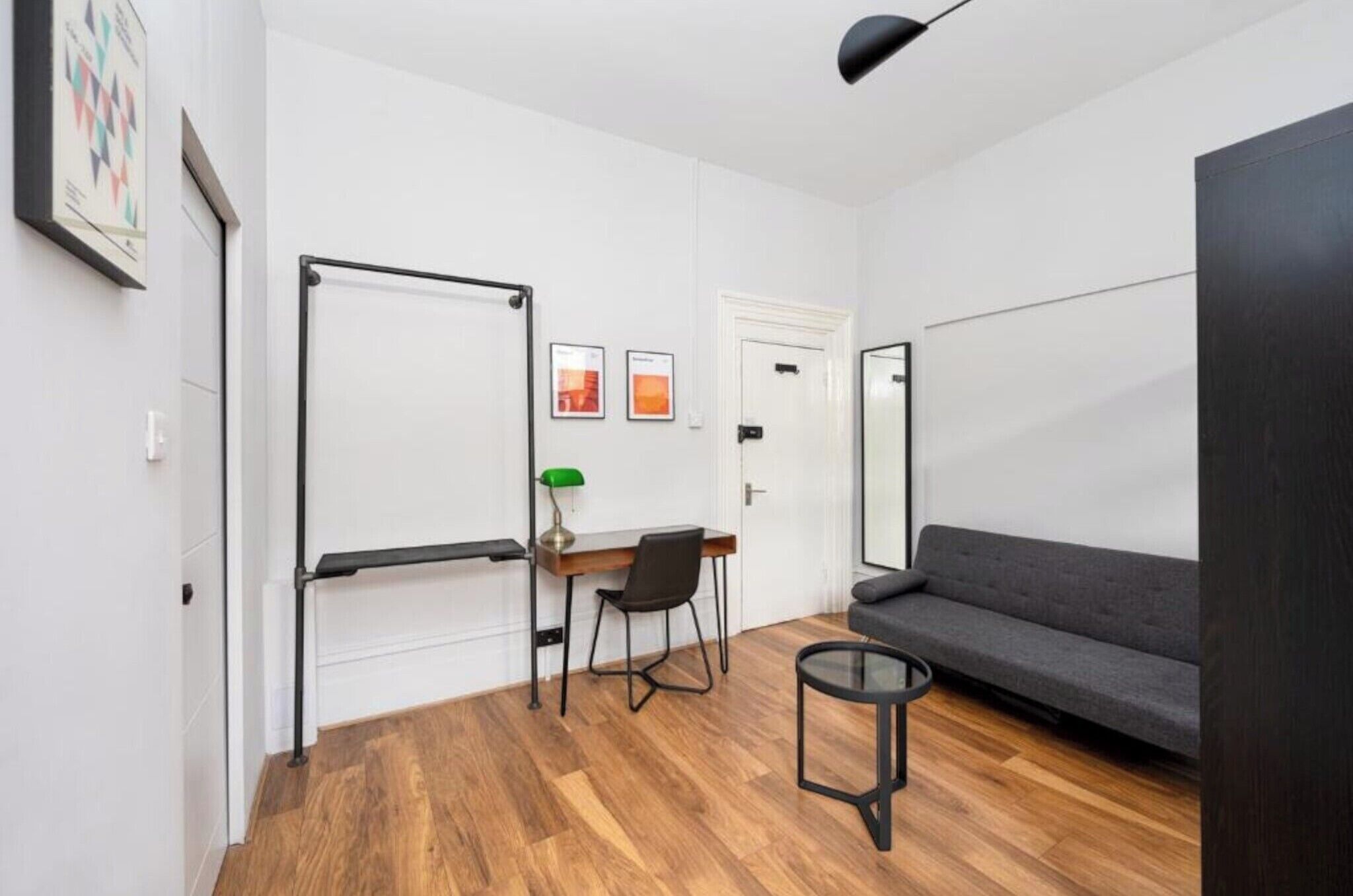 Ein modernes Zimmer mit Schreibtisch, Stuhl, Sofa und kleinem runden Tisch.