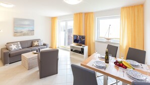 Un salon moderne avec un canapé, une table basse et un coin repas avec une table mise pour deux personnes.